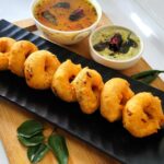 Sambar Vada – golden lentil fritters soaked in aromatic South Indian sambar, garnished with onions and coriander.